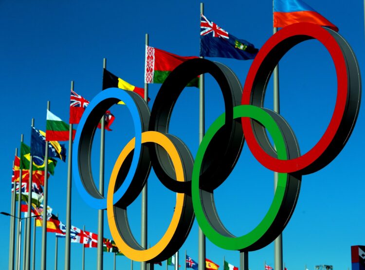 The Olympic Rings stand in front of the flags of Nations in the Olympic Park.